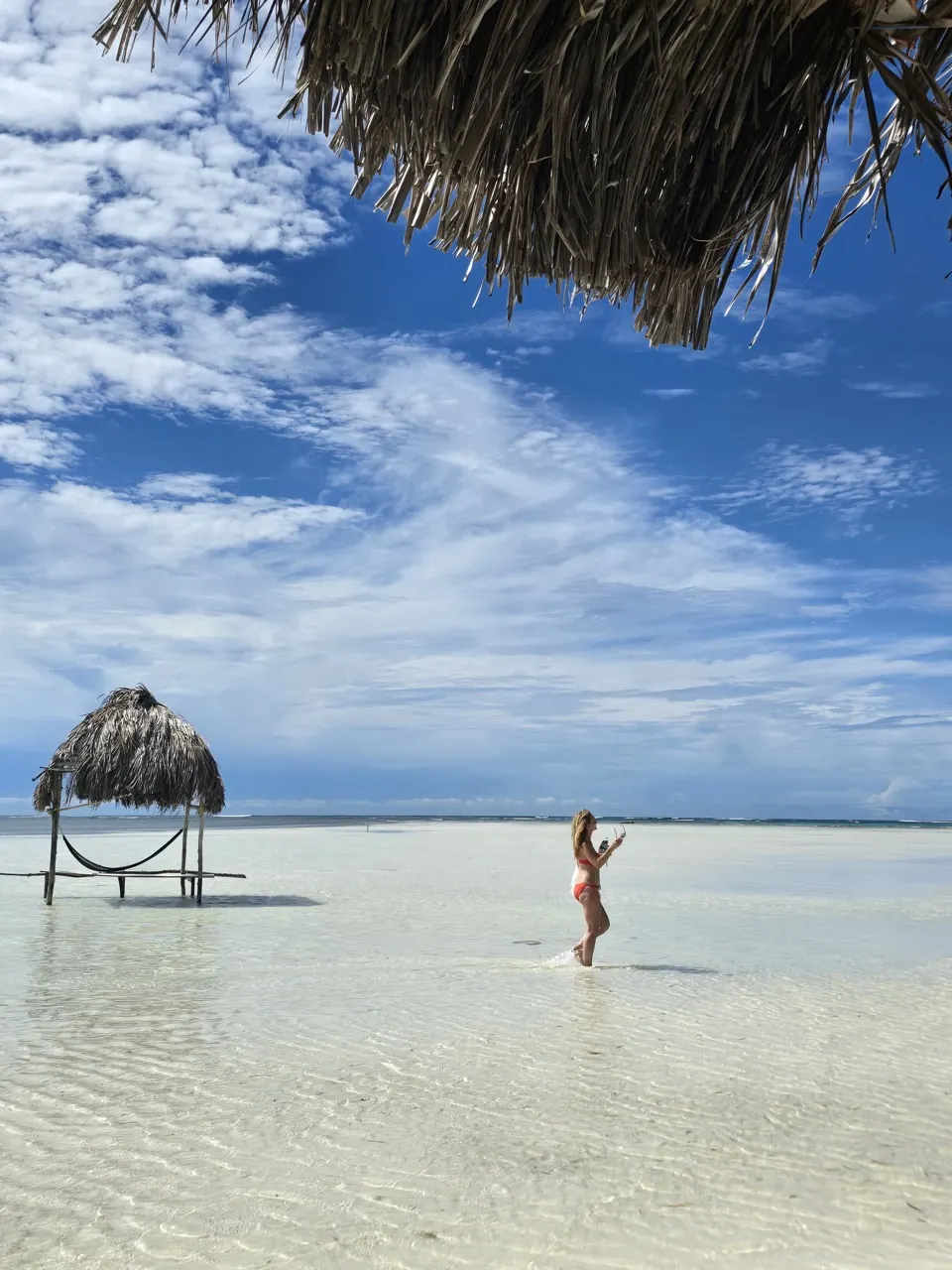 Turquoise San Blas sandbar with a thatched hut and hammock over clear shallow water
