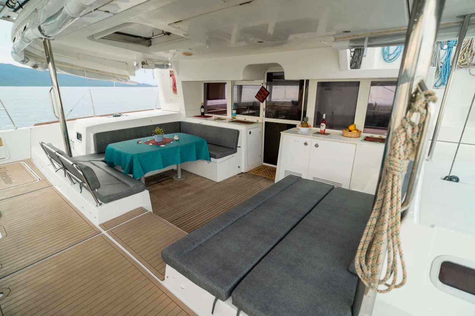 Aft cockpit of the Lagoon 450 set for dinner beside a full-width sun lounger, teak deck