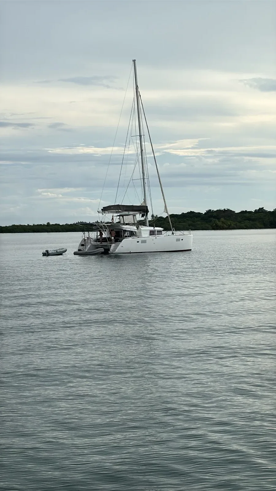 The Lagoon 450 at anchor on a calm grey morning with the dinghy tied astern