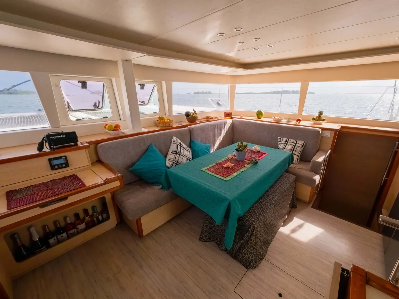 Salon of the Lagoon 450 with panoramic windows, wine storage and a teal dining table