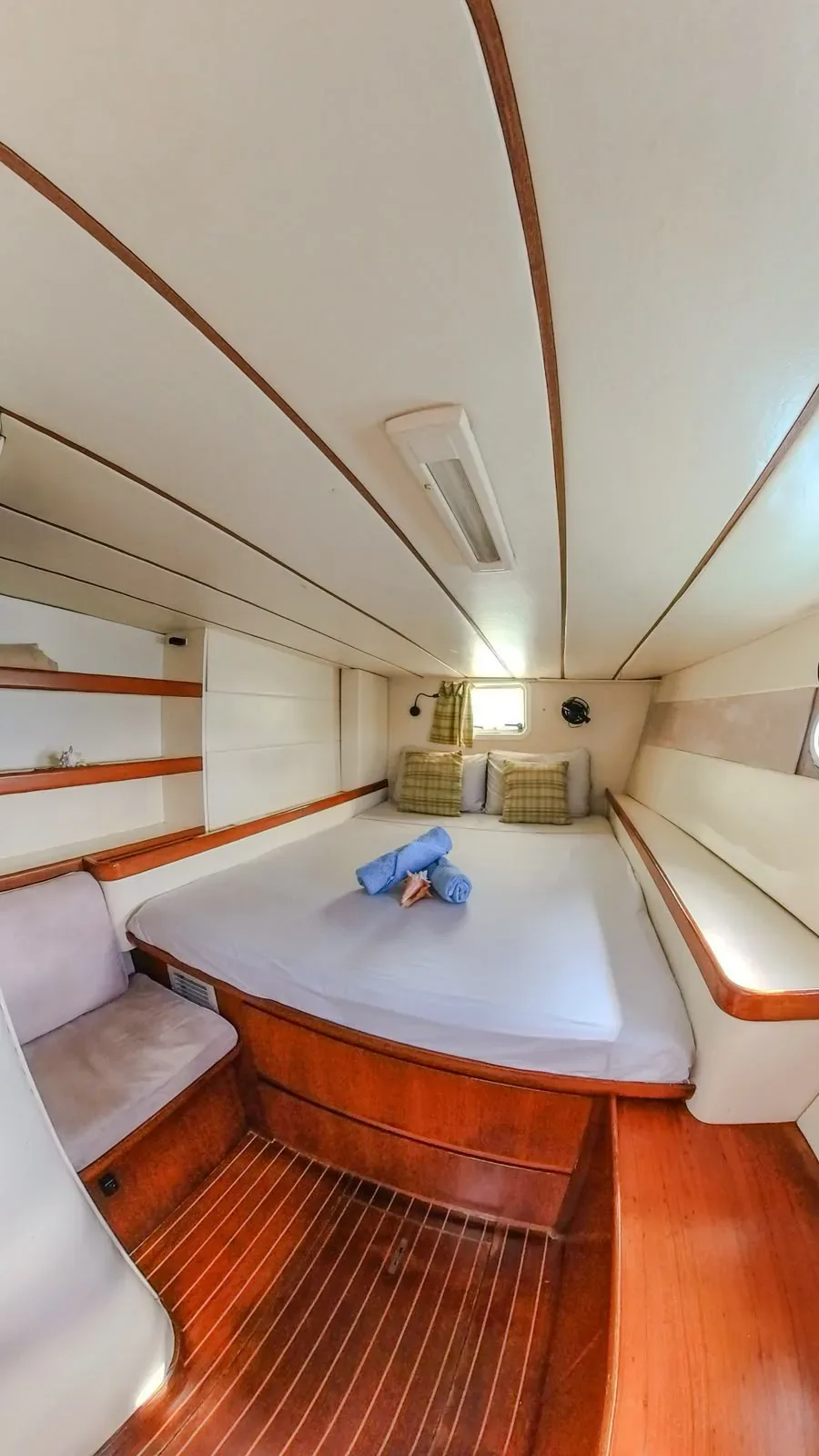 Guest cabin aboard the Lagoon 55 with cream upholstery and varnished teak