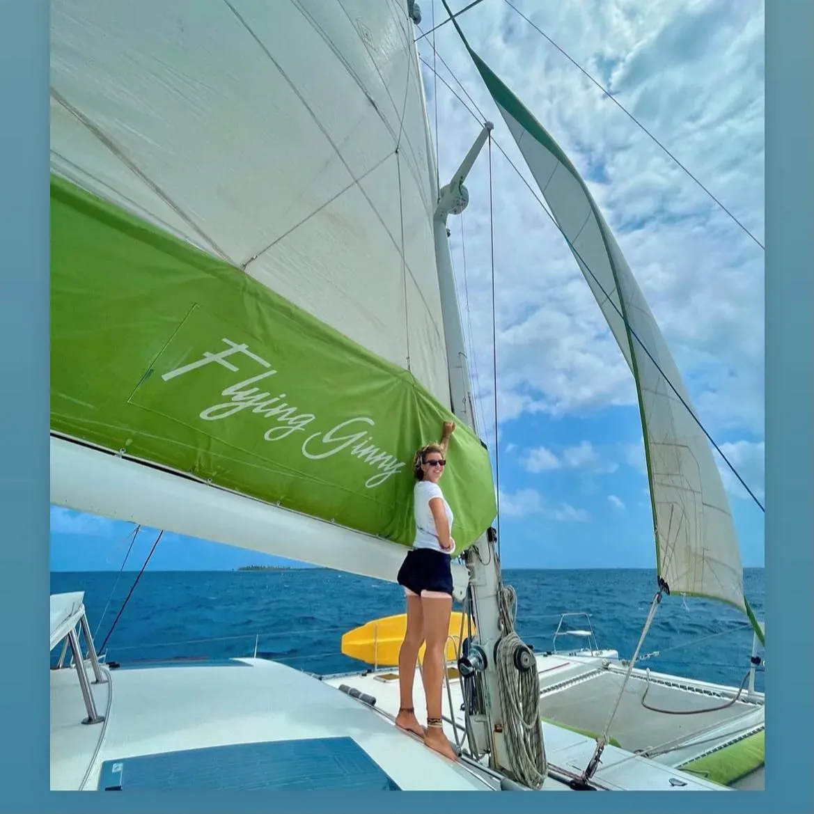 The Lagoon 55 sailing under her green mainsail with crew on the foredeck