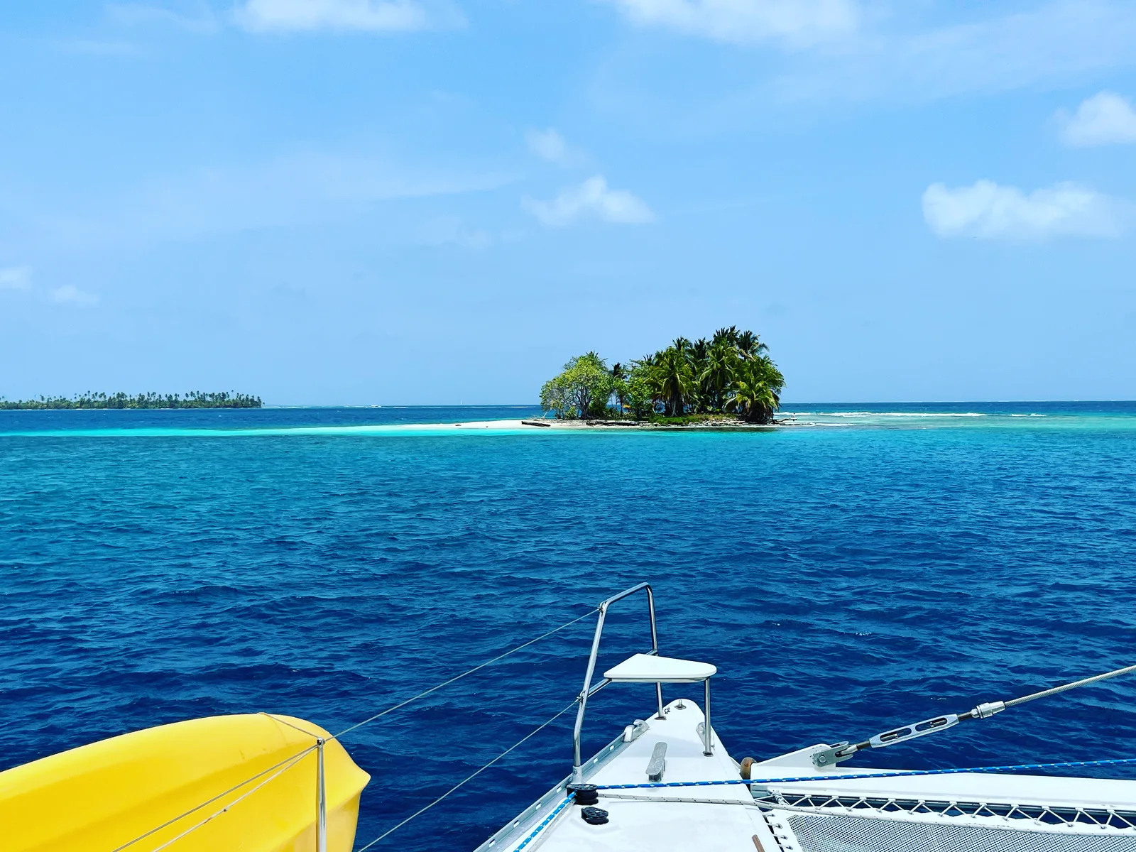 View from the bow of the Lagoon 55 across deep blue water to a single palm island
