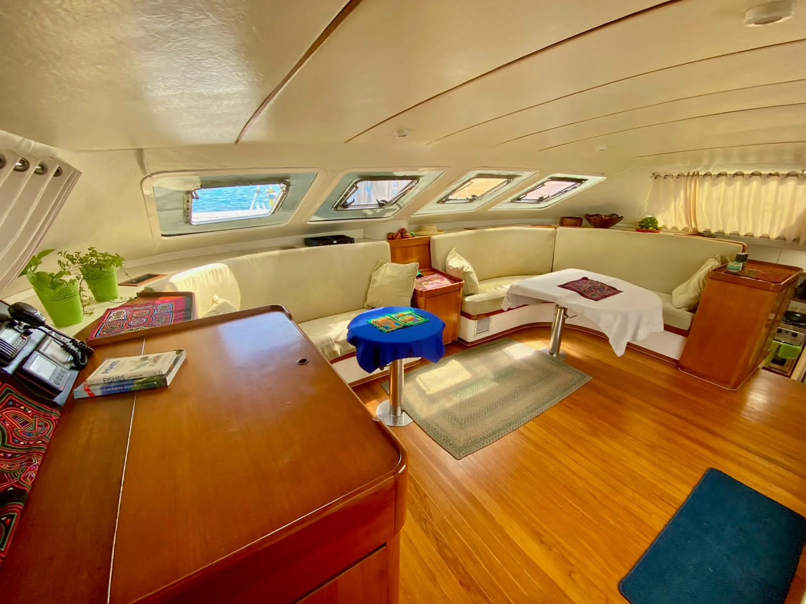 Saloon of the Lagoon 55 with a curved cream settee, teak sole, nav station and hull windows