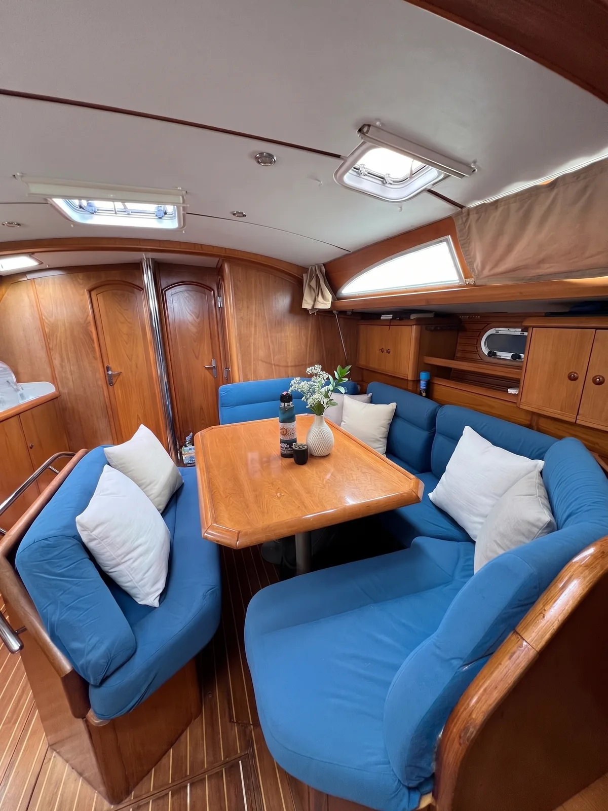Saloon of the Jeanneau 45.2 with blue wraparound seating around a wooden dining table