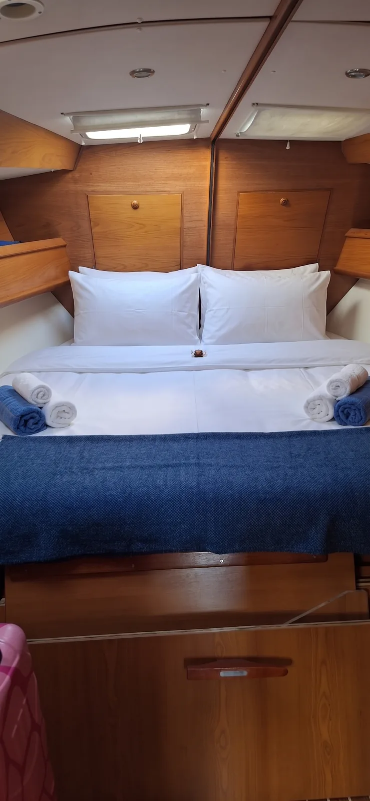 Double cabin with a made-up bed, rolled towels and a blue throw