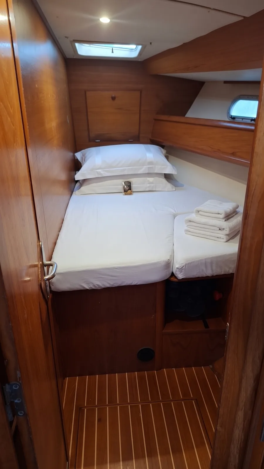 Guest cabin with a double berth, fresh towels and an overhead hatch