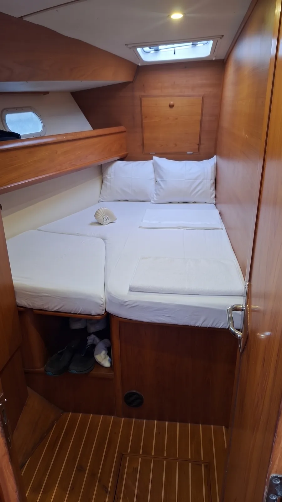 Second guest cabin with a double berth, a porthole and an overhead hatch