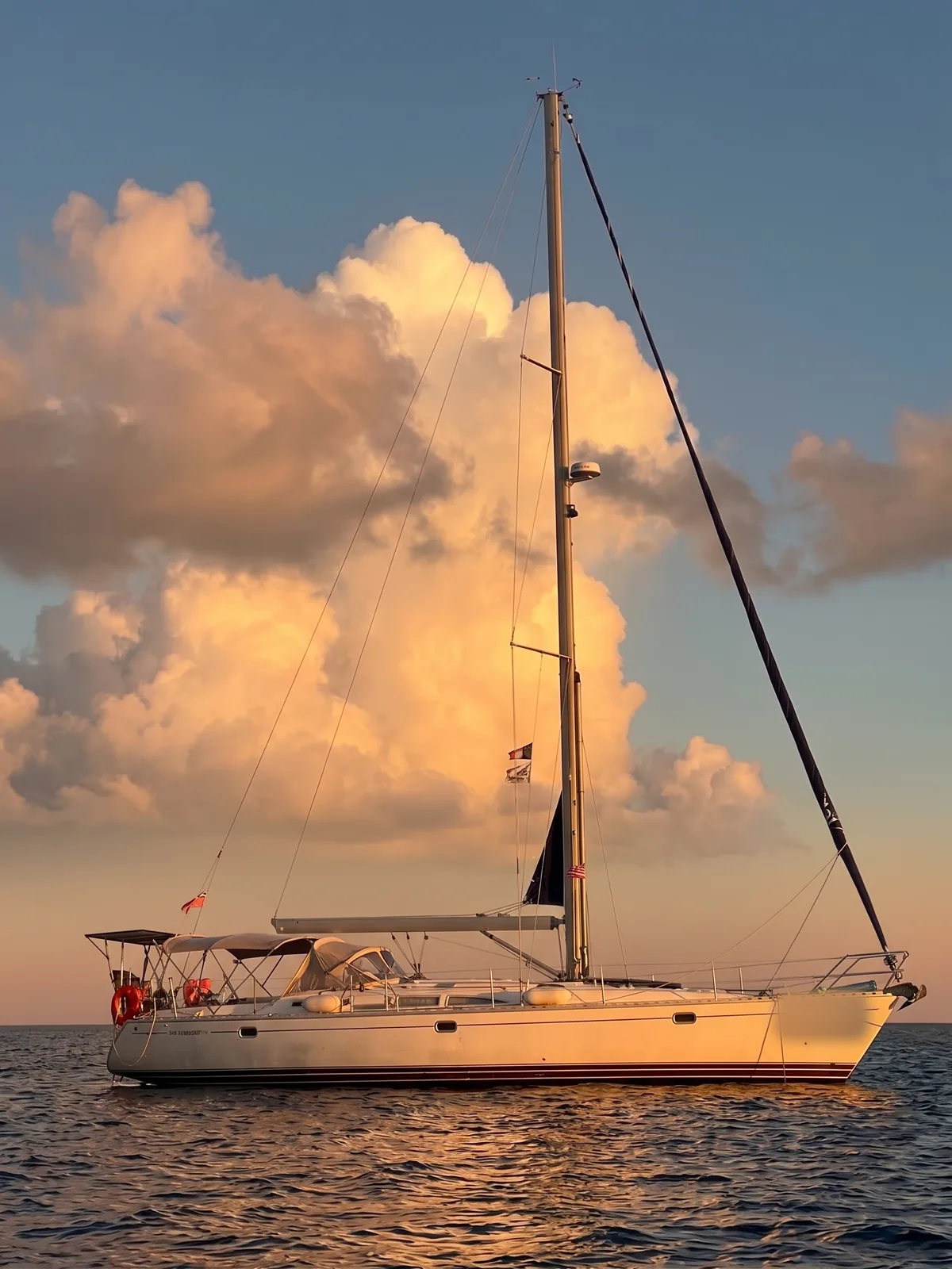 The Jeanneau 45.2 at anchor under a tall cloud at sunset