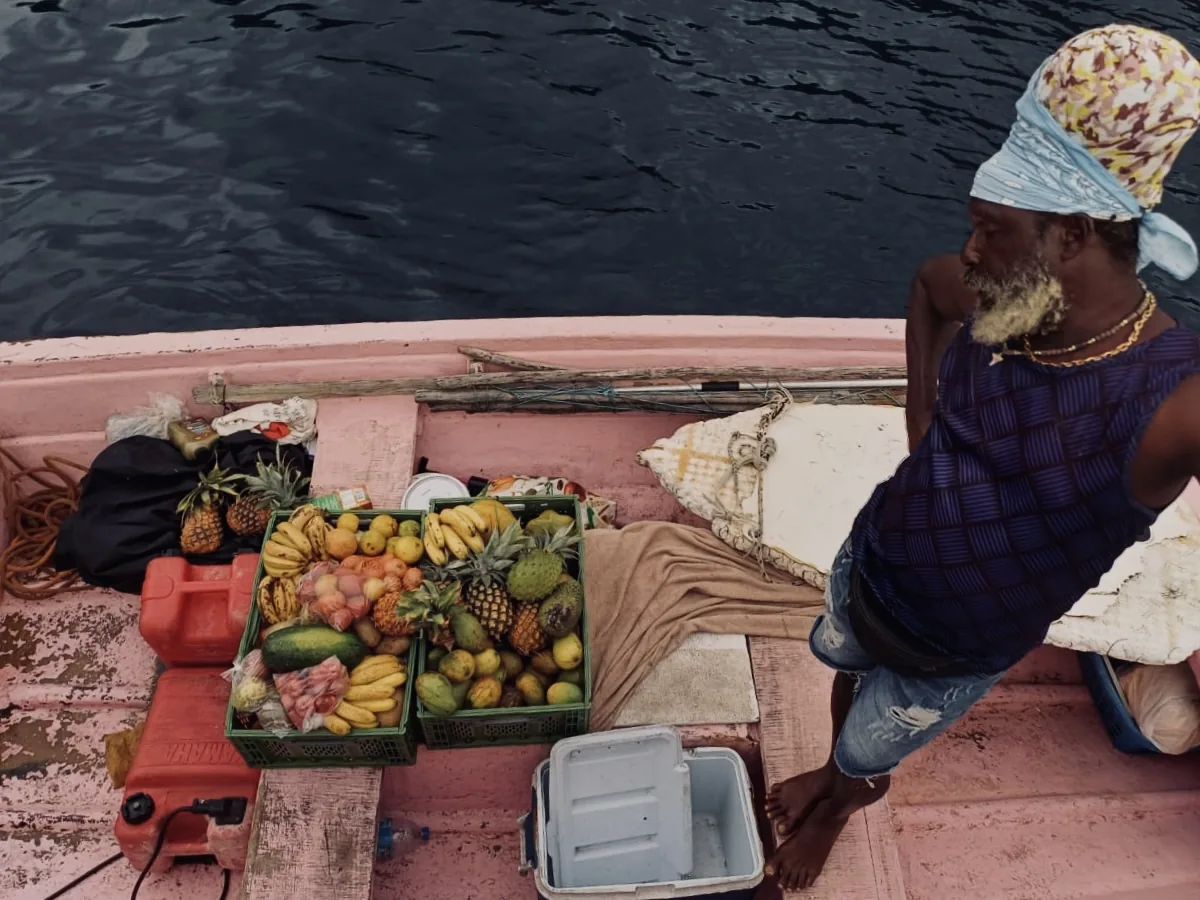 A fruit boat alongside, loaded with pineapples, bananas, melons and mangoes
