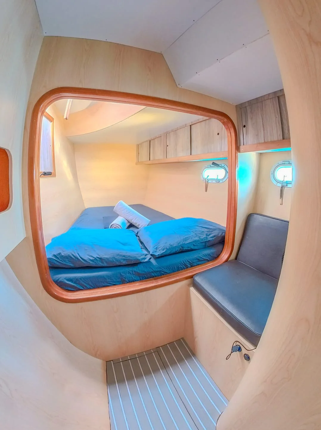 Double cabin with blue bedding and a seat, seen through the doorway