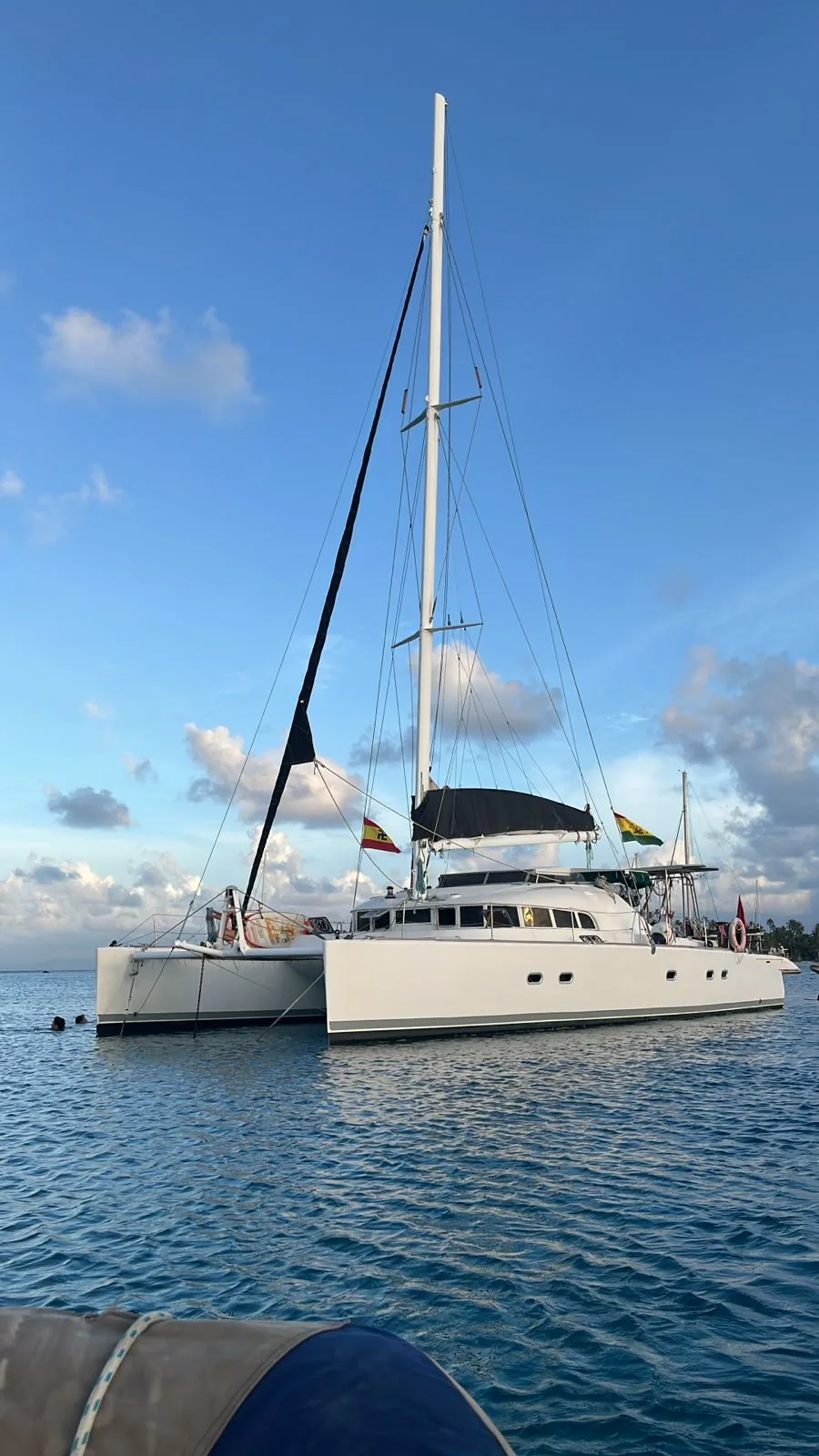 The catamaran at anchor at sunset, sails furled