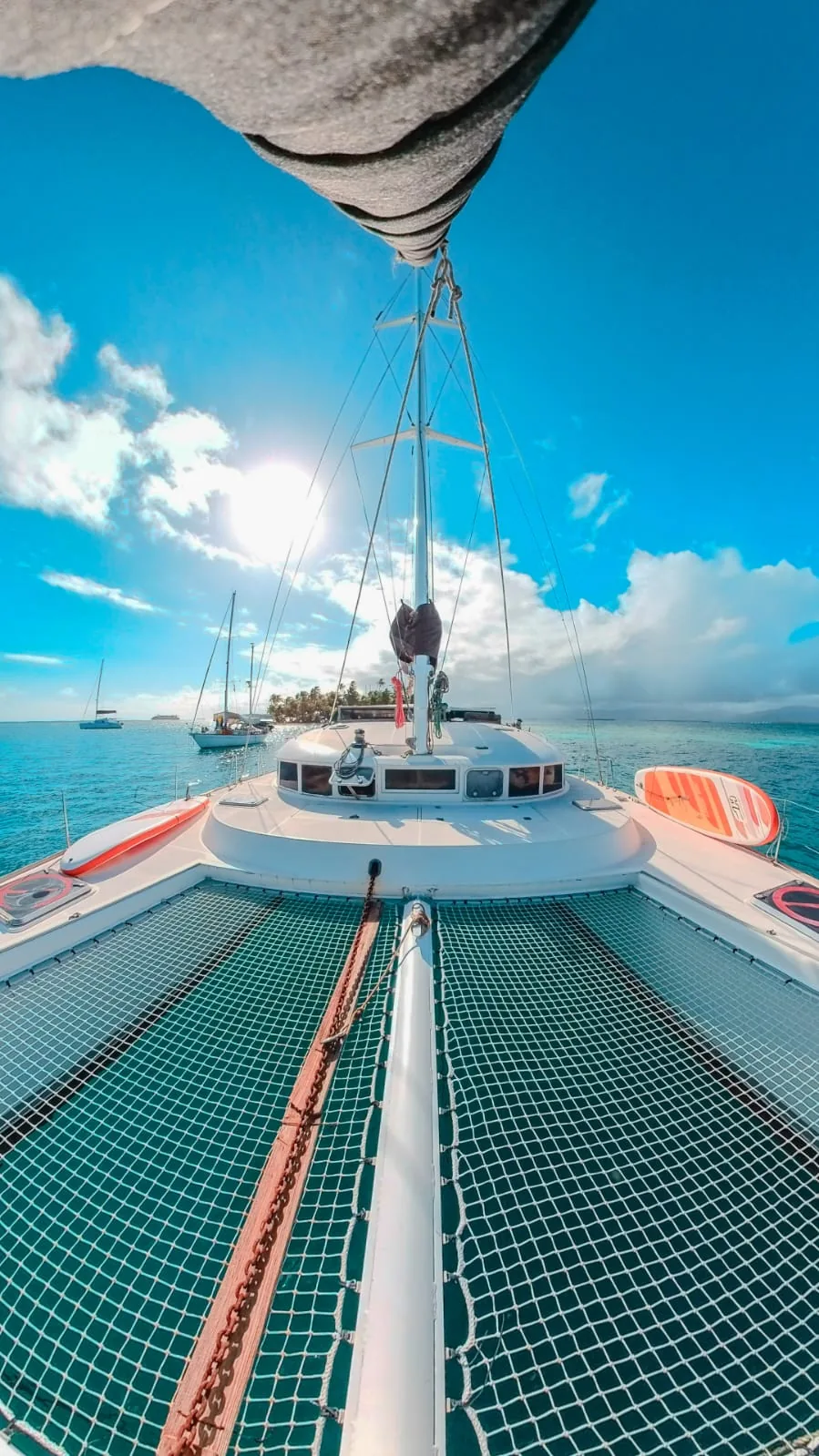 Trampoline nets and bow in bright sun with other boats at anchor