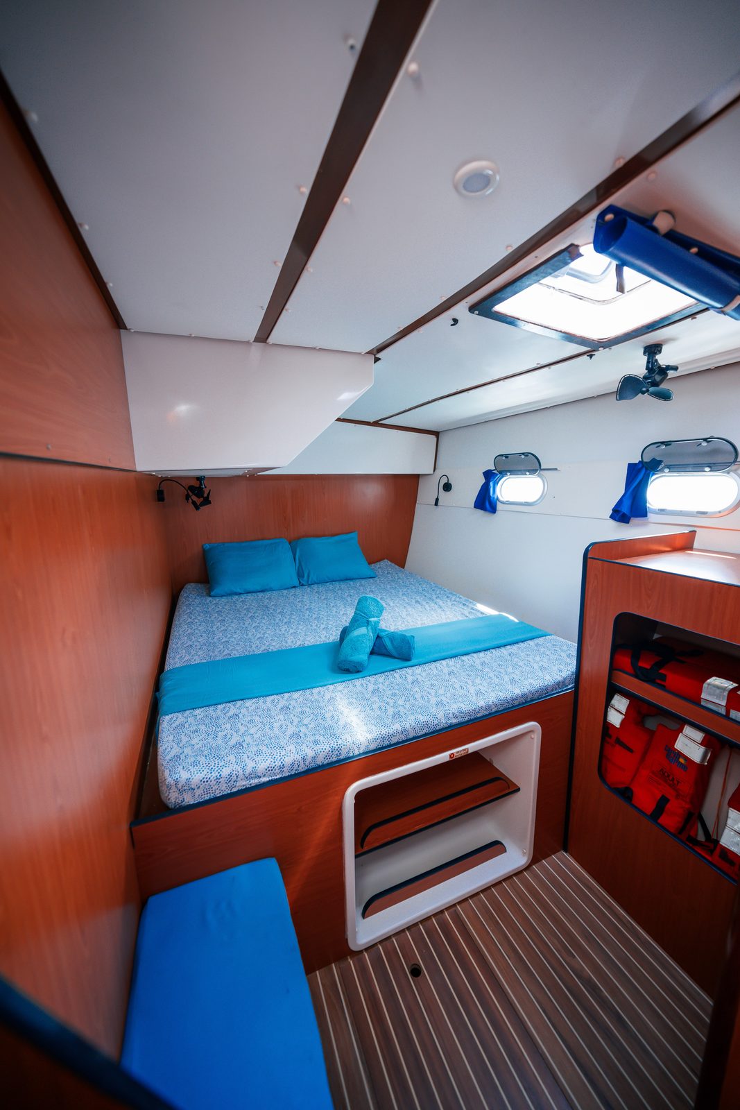 Cabin with blue bedspread, overhead hatch and cherry timber trim