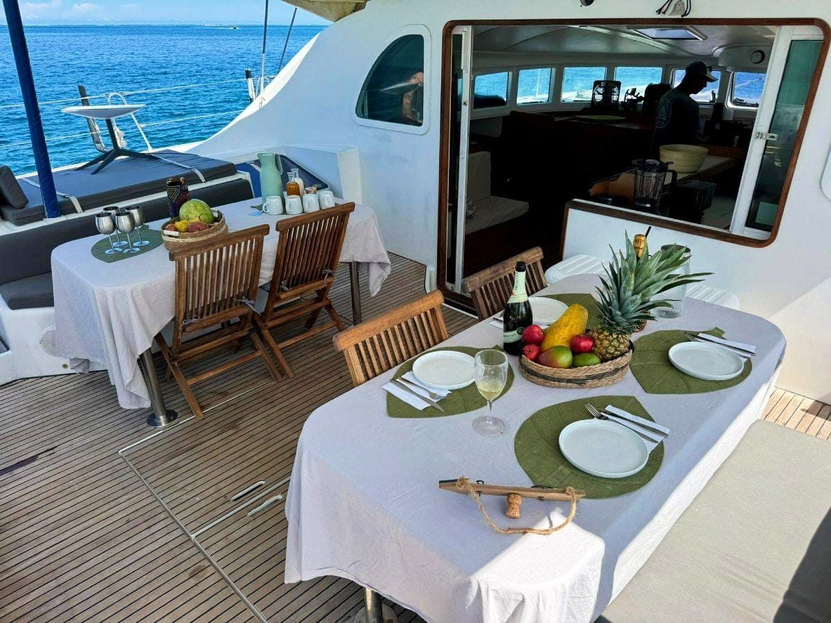 Cockpit table laid with white linen and place settings, islands beyond