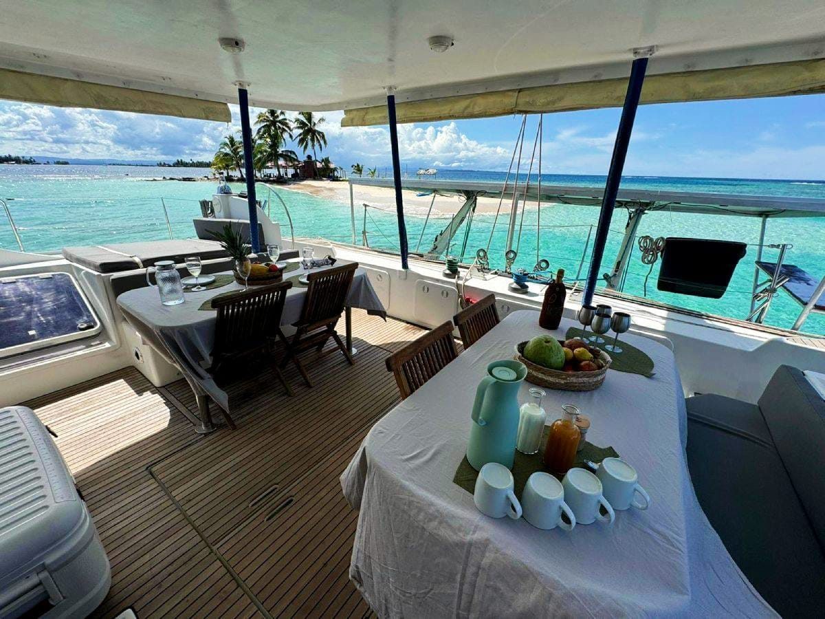 Cockpit dining table set with fresh fruit, looking out over turquoise water