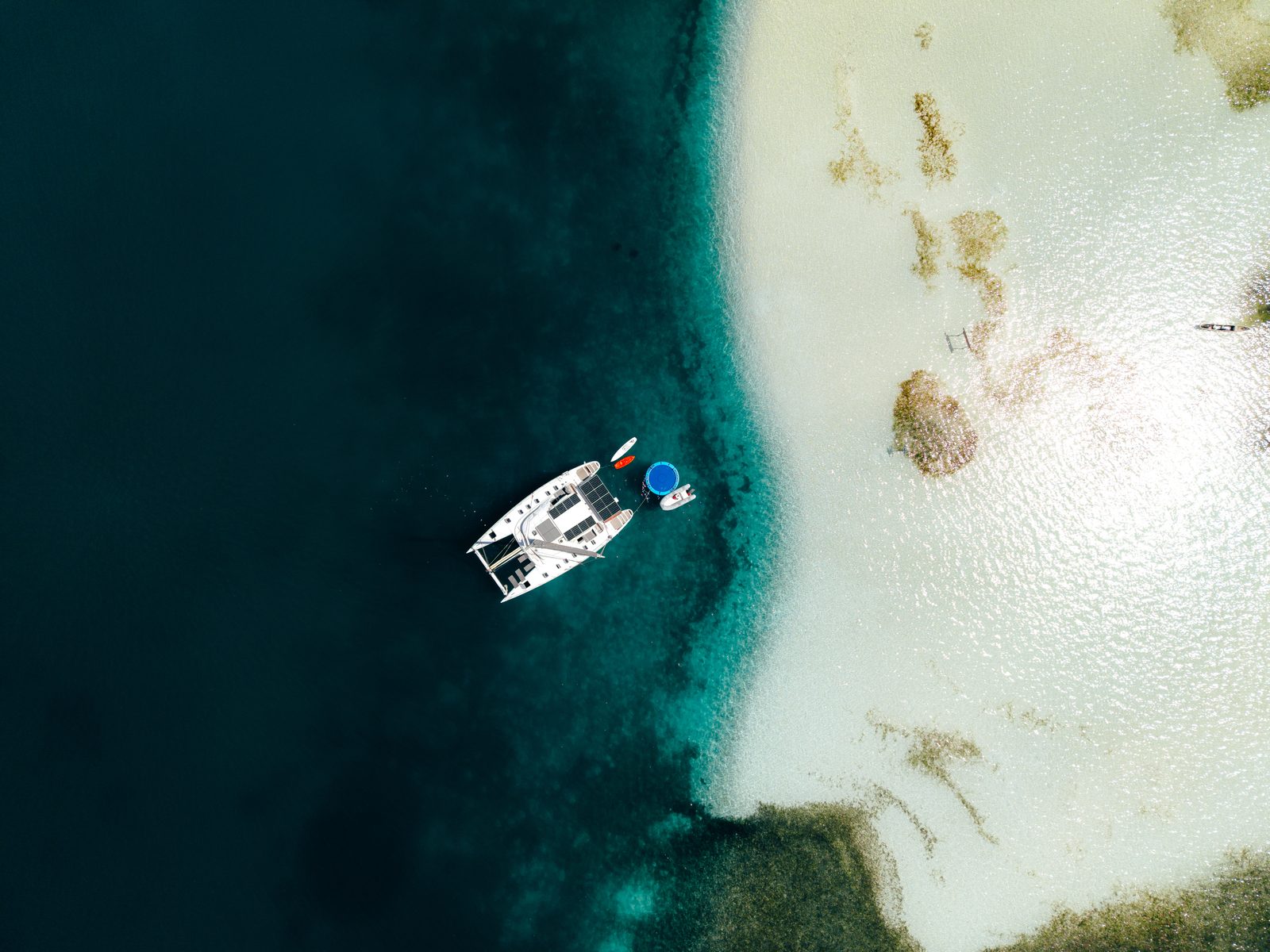 Overhead drone view of the catamaran anchored beside a white sandbank