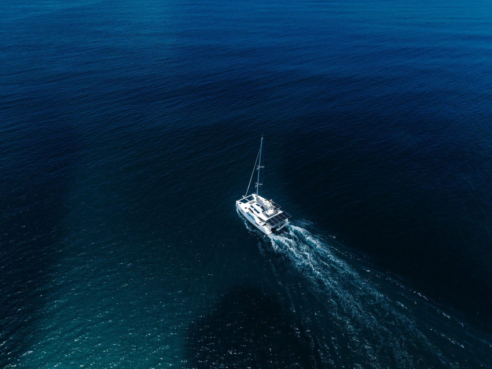 The catamaran under way in deep blue water, seen from the air
