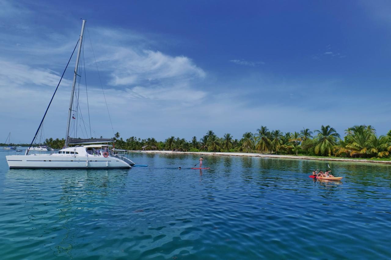 The 57-foot catamaran anchored in calm water beside a palm-fringed cay