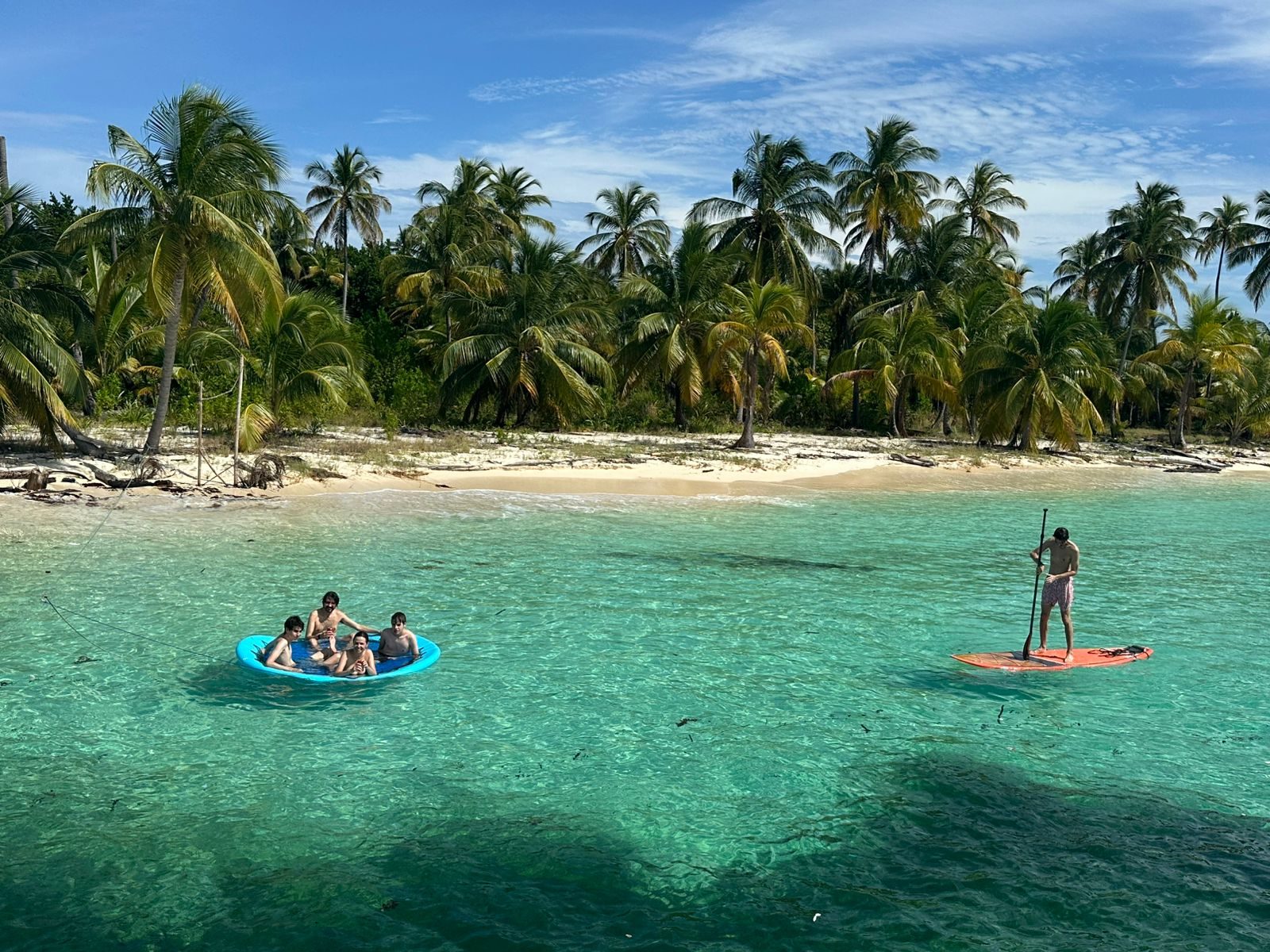Guests paddleboarding and kayaking off a palm-fringed San Blas beach